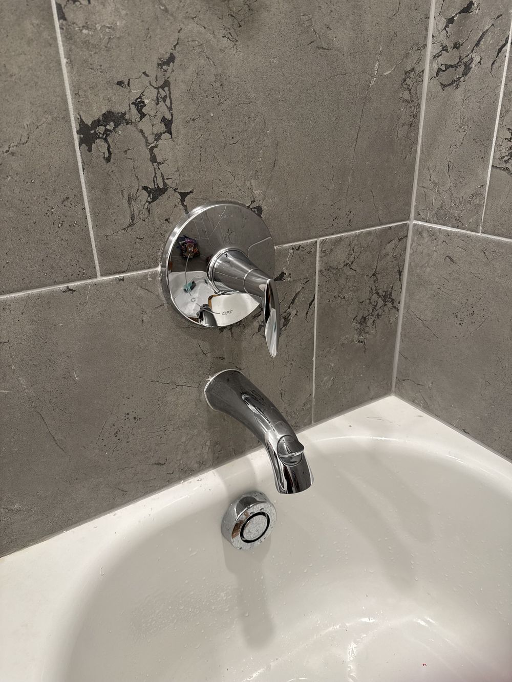 New chrome shower valve and tub spout on marble tile
