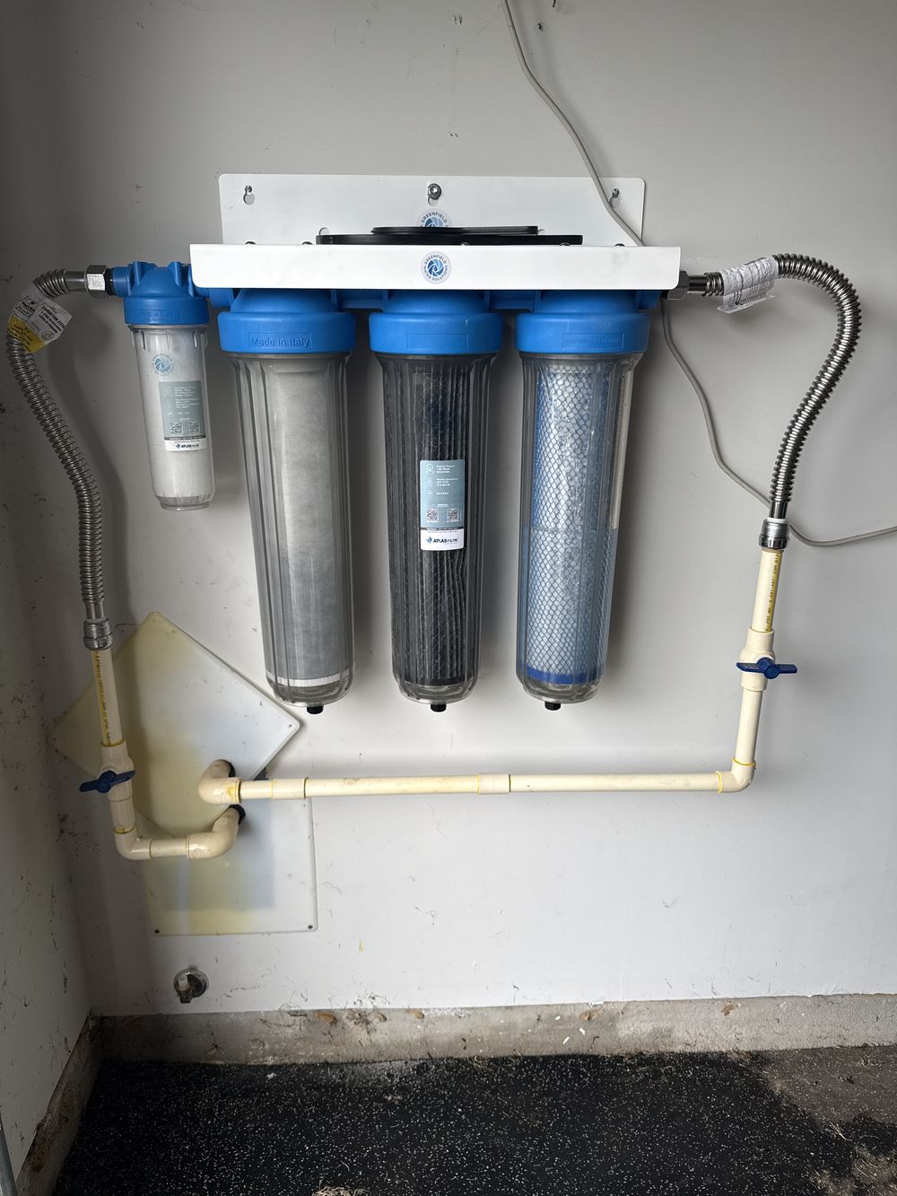 Four-stage water filtration system mounted on a garage wall